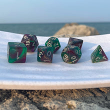 Load image into Gallery viewer, Swamp Orchids Dice Set Amid the purple and green swirls of these dice, the mind conjures images of flowers in the swamp, an aurora in the sky, or a court jester playing for the king. Whether you are a druid of decay, a joker, or a student of the arcane, you’ll be able to appreciate the unique patterns and the silver inking that impart a subtle beauty.