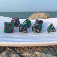 Load image into Gallery viewer, Swamp Orchids Dice Set Amid the purple and green swirls of these dice, the mind conjures images of flowers in the swamp, an aurora in the sky, or a court jester playing for the king. Whether you are a druid of decay, a joker, or a student of the arcane, you’ll be able to appreciate the unique patterns and the silver inking that impart a subtle beauty.
